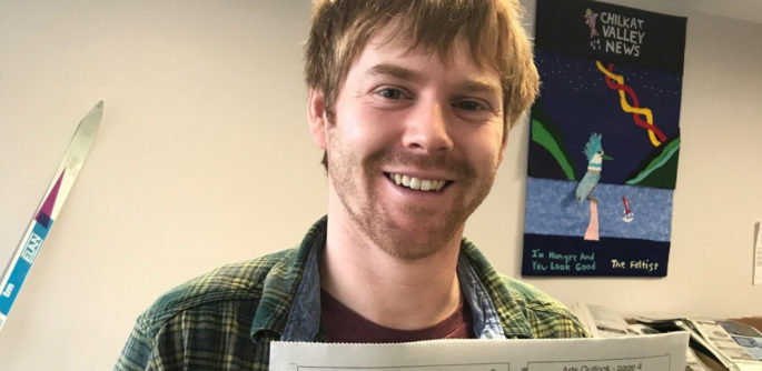 Chilkat Valley News editor Kyle Clayton holds a newspaper and smiles